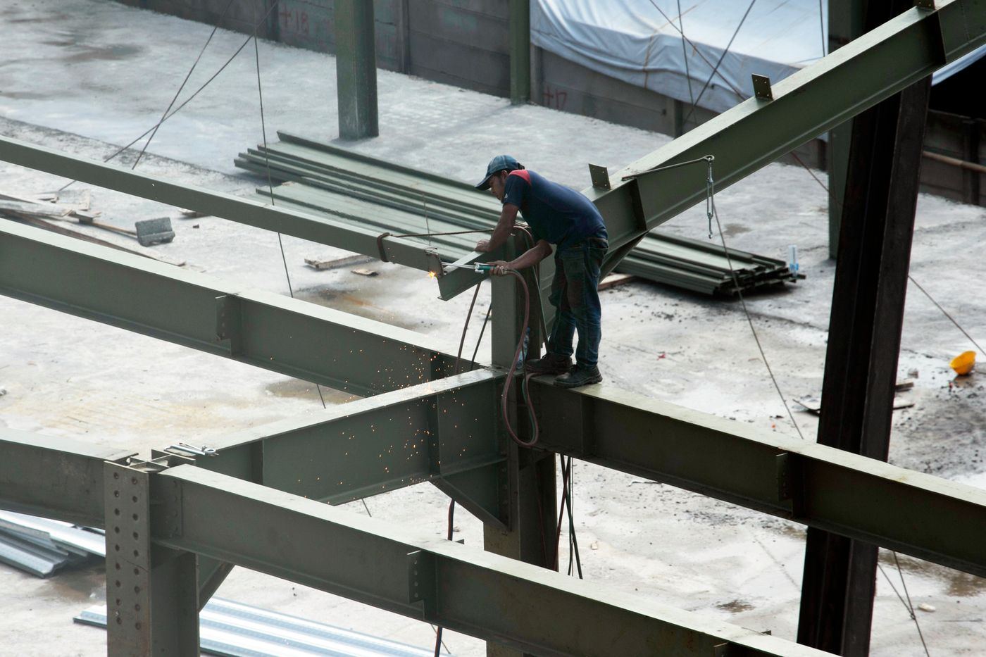 A worker cutting steel on a primed beam within a partly erected steel frame